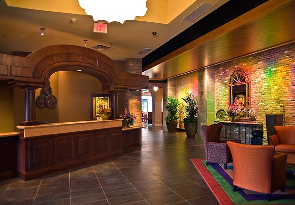 Warmly lit hotel lobby featuring a wooden reception desk, colorful seating, and ornamental plants, located at Fairfield Inn & Suites Baltimore Downtown/Inner Harbor, ideal for Preakness Stakes accommodations.