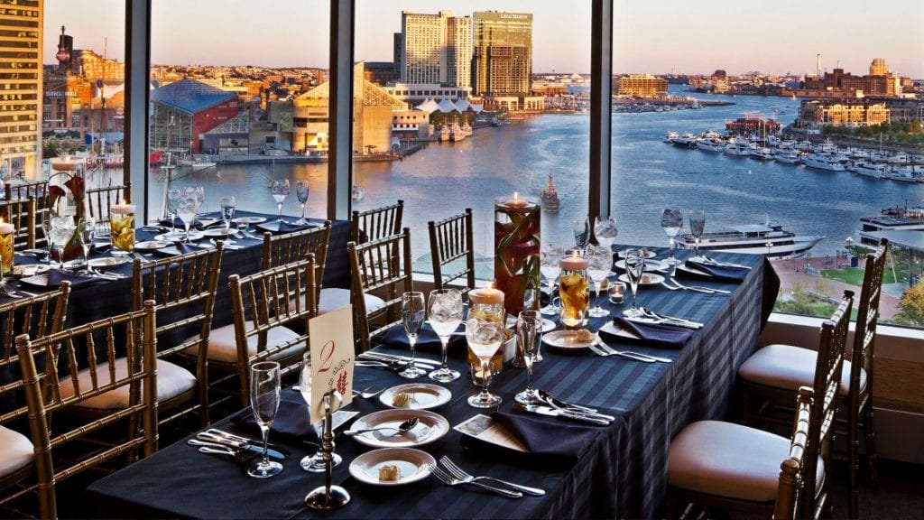 Dining setup with a scenic view at the Hyatt Regency Baltimore Inner Harbor overlooking the city and waterfront, ideal for discovering and connecting during Baltimore area road trips.
