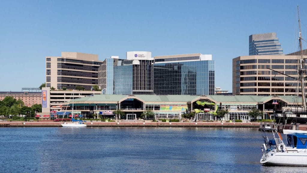View of the Hyatt Regency Baltimore Inner Harbor, showing its modern glass facade and location by the waterfront, ideal for visitors attending the Preakness Stakes.