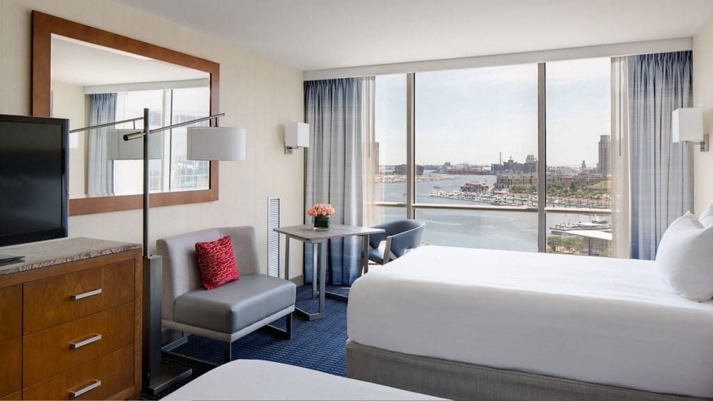 A spacious hotel room at the Hyatt Regency Baltimore Inner Harbor, featuring a panoramic harbor view, ideal for visitors to the Preakness Stakes near Pimlico Race Course.