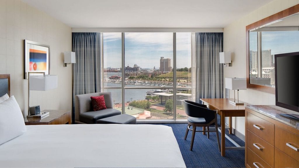 A spacious, modern room at the Hyatt Regency Baltimore Inner Harbor, featuring a large window view of the harbor, ideal for visitors to the Preakness Stakes at Pimlico Race Course.