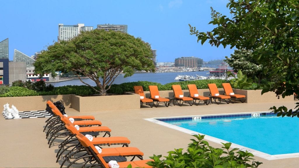 Outdoor pool area with orange lounge chairs at the Hyatt Regency Baltimore, near Baltimore's Inner Harbor, offering accommodations close to Pimlico Race Course for the Preakness Stakes.