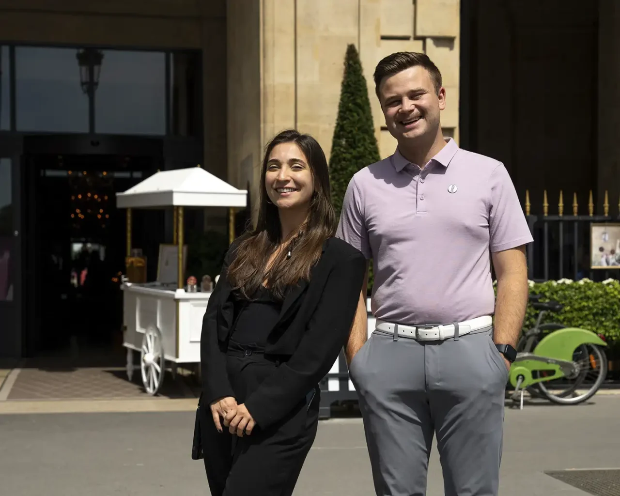 Two on-site hosts stand smiling outside the Ritz-Carlton Reynolds, Lake Oconee, promoting luxury travel and tours for the Masters Golf Tournament.