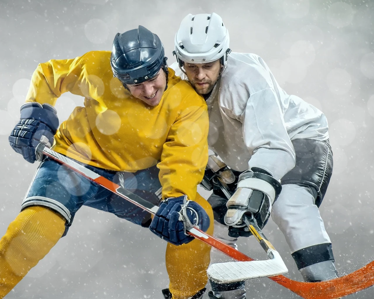 Two hockey players in yellow and white jerseys compete intensely for the puck under snowy conditions, ideal for those considering hockey travel and ticket packages for major events.