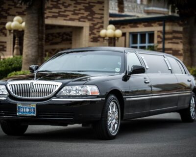 Luxury black limousine parked outside a building, highlighting the expert pre-travel and high-quality sports travel experiences offered by Roadtrips with At-Your-Service Desk™ assistance.
