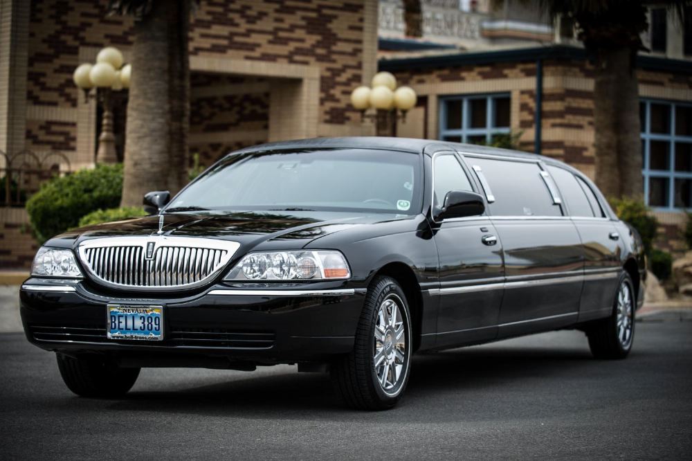 Luxury black limousine parked outside a building, highlighting the expert pre-travel and high-quality sports travel experiences offered by Roadtrips with At-Your-Service Desk™ assistance.