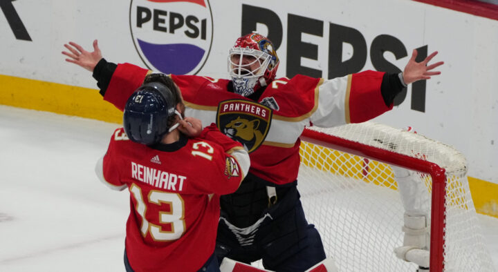 Two hockey players in red Florida Panthers jerseys celebrate near the goal during a game, emphasizing excitement, possibly relating to the Stanley Cup Final Travel Package Rates.