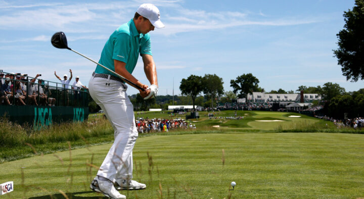 A golfer wearing a turquoise shirt swings at a golf ball at a US Open Golf Championship event, demonstrating the exclusive experiences offered in the US Open Golf travel package rates.