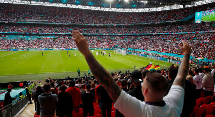 Fans cheer at a crowded stadium during a championship football match, capturing the excitement of a live sports event and the dedication of the spectators.