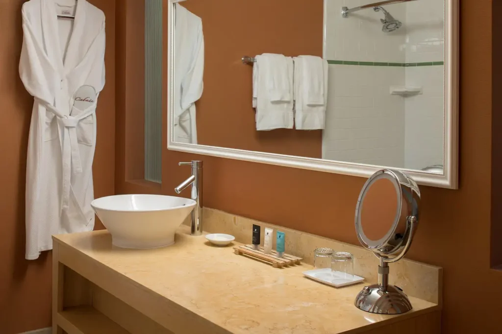Elegant bathroom at Cabana Hotel in Palo Alto, featuring a modern vessel sink, mirrored walls, and complimentary bathrobes, ideal accommodation for visitors looking for luxury hotels in the San Jose area.