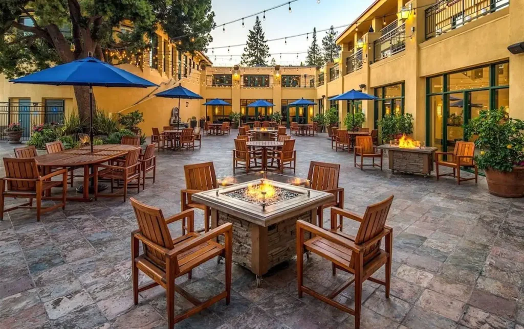 Outdoor seating area at Cabana Hotel in Palo Alto, featuring fire pits, umbrellas, and string lights, ideal for South Bay Area and Palo Alto hotel seekers.