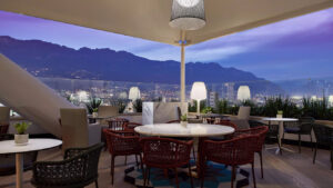 An elegant rooftop seating area at the Westin Monterrey Valle, featuring stylish furniture and panoramic views of a city surrounded by mountains, ideal for World Cup hotel accommodations.