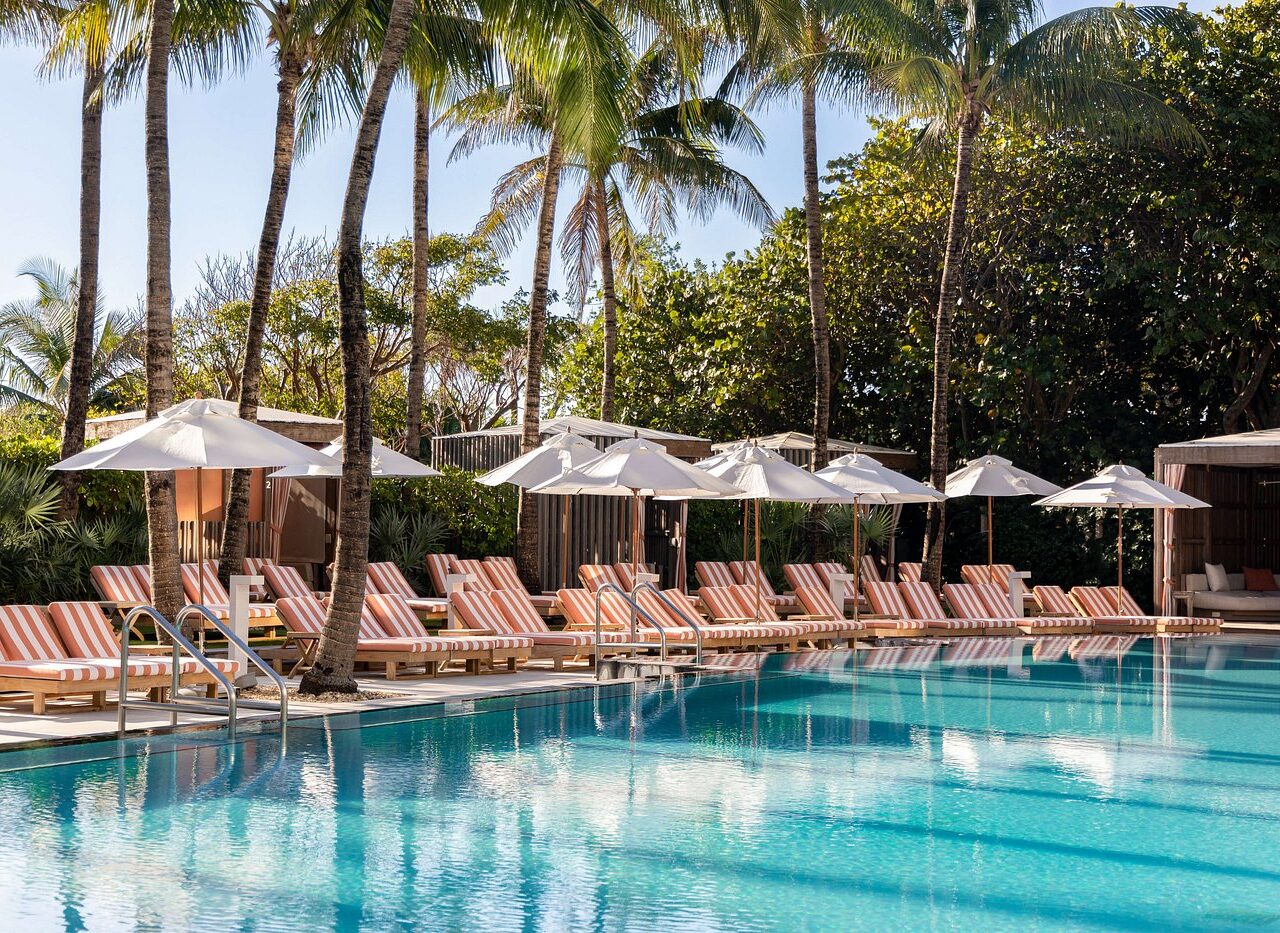 Stripe-patterned deck chairs and white umbrellas line a serene pool at W South Beach, Miami.