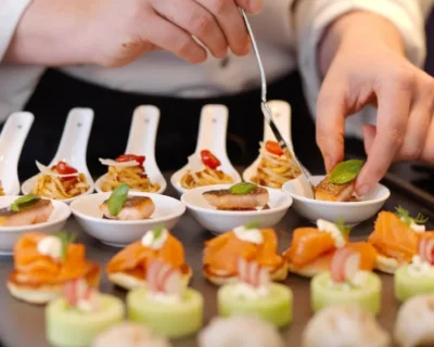 A chef carefully prepares an array of gourmet appetizers, highlighting the exclusive group experiences and full suite of event services offered by Roadtrips.