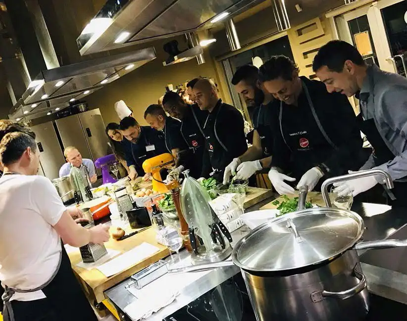 Group of people engaging in a cooking class, preparing food together in a well-equipped kitchen, reflecting Milan's rich culinary traditions, ideal as an add-on to exploring Milan's highlights.