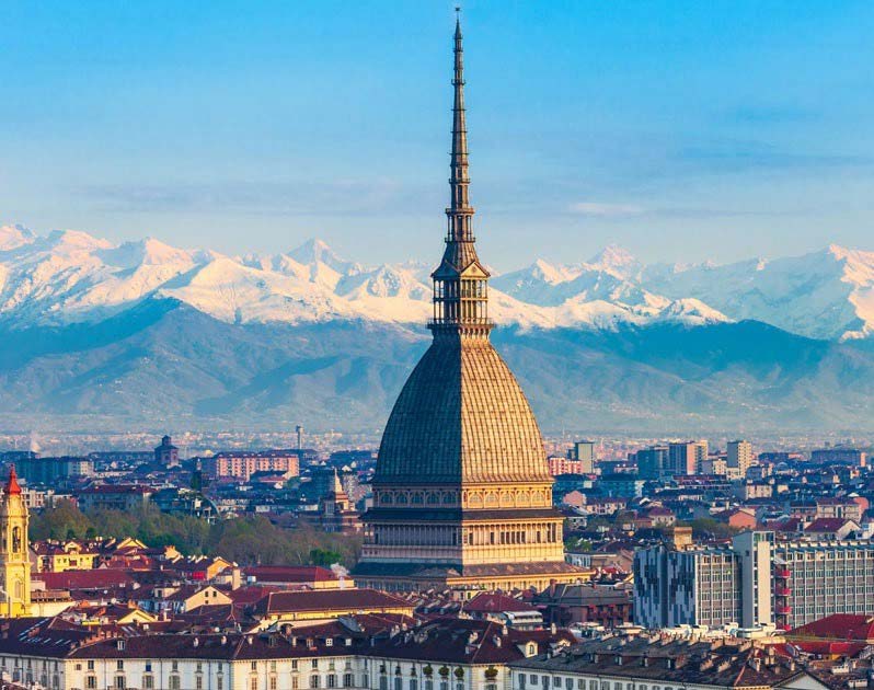 View of Turin with the Mole Antonelliana dominating the skyline against a backdrop of snow-capped mountains, ideal for exploring ahead of the Winter Games or joining a Milan food adventure.