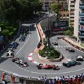 Formula 1 cars racing through the Fairmont Hairpin at the Monaco Grand Prix, with fans watching from apartment balconies abov