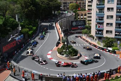 Formula 1 cars racing through the Fairmont Hairpin at the Monaco Grand Prix, with fans watching from apartment balconies abov